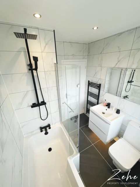 Marble-effect wall tiles, black shower fittings and a modern vanity in a finished bathroom