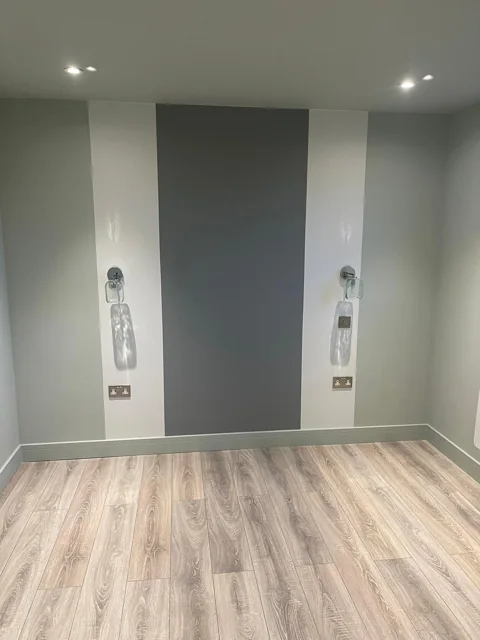 Charcoal feature wall, wall lights and timber-effect bedroom flooring