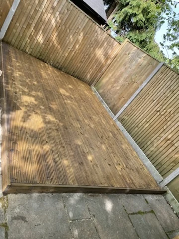 Renewed timber decking beside the garden fence and paved patio
