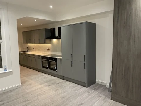 Grey fitted kitchen with integrated appliances, timber-effect flooring and full-height storage