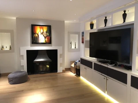 Living room with a television media wall, fireplace and warm accent lighting