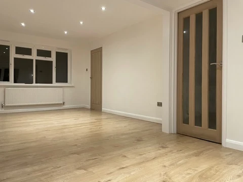 Refurbished living room with timber-effect flooring, white walls and oak doors
