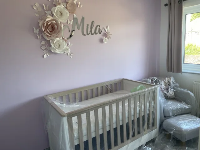Decorated nursery with a floral wall feature and white cot