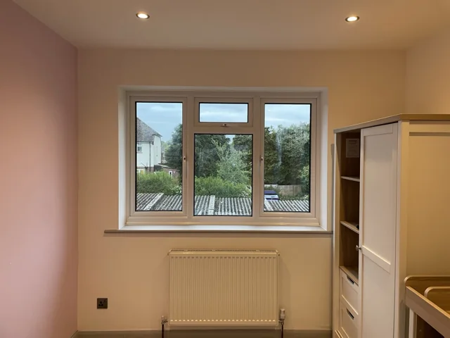 Refinished room with soft pink walls, carpet and a bright window