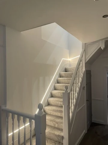 Finished staircase with grey carpet, white balustrade and accent lighting